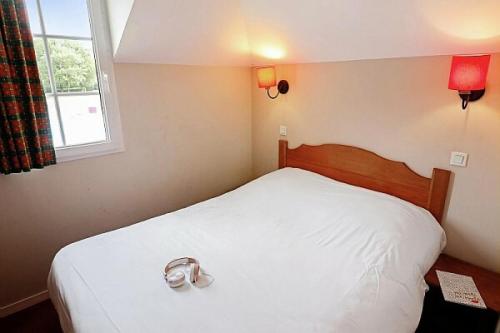 een slaapkamer met een wit bed met een paar schoenen erop bij La résidence du Lac - maeva Home - Appartement 2 pièces 5 personnes - Conf 694 in Monflanquin