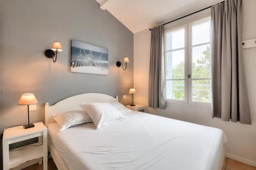 une chambre avec un lit blanc et une fenêtre dans l'établissement Les Maisons aux Restanques du Golfe de St Tropez - maeva Home - Maison duplex 4 pièces 8 personnes avec décoration raffinée - Prestige - super Home MAE-5654, à Grimaud