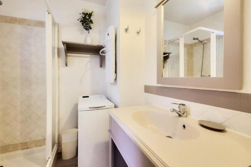 une salle de bain blanche avec un lavabo et un miroir dans l'établissement Les Maisons aux Restanques du Golfe de St Tropez - maeva Home - Maison duplex 4 pièces 8 personnes avec décoration raffinée - Prestige - super Home MAE-5654, à Grimaud