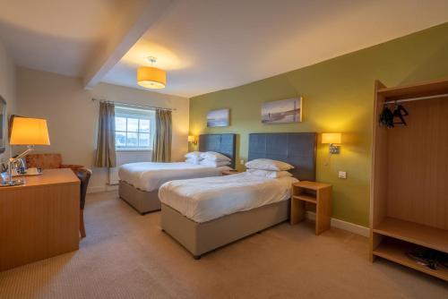 a hotel room with two beds and a desk at THE LORD NELSON HOTEL in Pembrokeshire