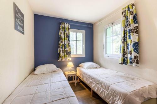 - 2 lits dans une chambre aux murs bleus et aux fenêtres dans l'établissement Les Maisons de Lacanau les Pins - maeva Home - Maison 4 pièces 8 personnes - Sélection MAE-7104, à Lacanau