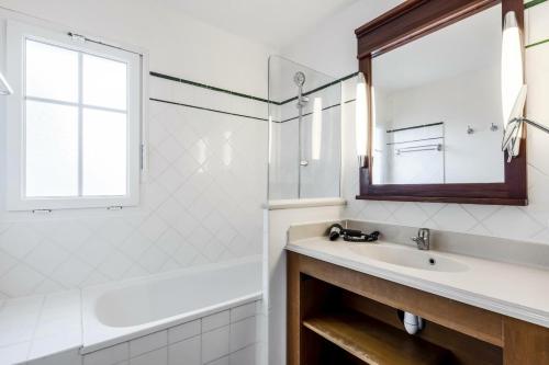 une salle de bain avec un lavabo, une baignoire et un miroir dans l'établissement Les Maisons de Lacanau les Pins - maeva Home - Maison 4 pièces 8 personnes - Sélection MAE-7104, à Lacanau