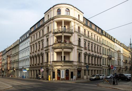 a large white building on the corner of a street at Limehome Dresden Hoyerswerdaerstraße in Dresden