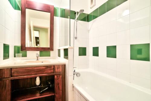 une salle de bain avec un lavabo, une baignoire et un miroir dans l'établissement Le Domaine du Golf de Pinsolle - maeva Home - Appartement 2 pièces 6 personnes - Prestige MAE-7084, à Soustons