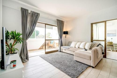 sala de estar con sofá y ventana grande en Spacious 1 bed in Vilamoura, Fast Wifi & Pool, en Quarteira