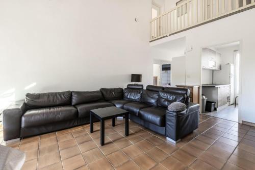 een woonkamer met een zwarte leren bank en een tafel bij Haute Plage - maeva Home - Maison 5 pièces 8 personnes - Prestige 214 in La Grande-Motte