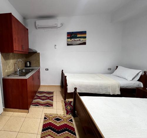 een kleine kamer met 2 bedden en een wastafel bij Tourists Guest House in Gjirokastër