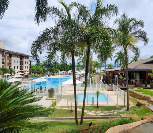 a swimming pool with palm trees in a resort at Life Resort, Beira Lago Paranoá in Brasilia