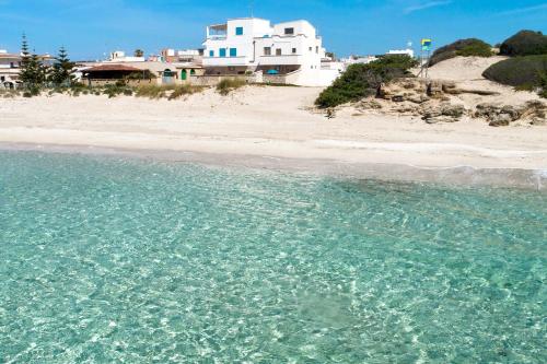 サン・ピエトロ・イン・ベヴァーニャにあるBlusea Beach Apartmentsの白い家と海のビーチ