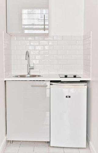 - une cuisine blanche avec un évier et 2 réfrigérateurs dans l'établissement Appartement central Montparnasse, à Paris