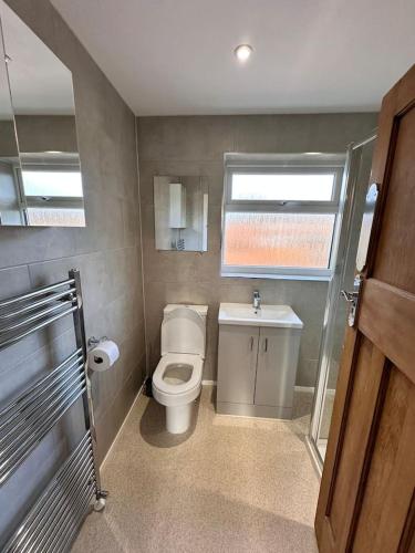 a bathroom with a toilet and a sink and a window at City centre home in Canterbury with free parking in Canterbury