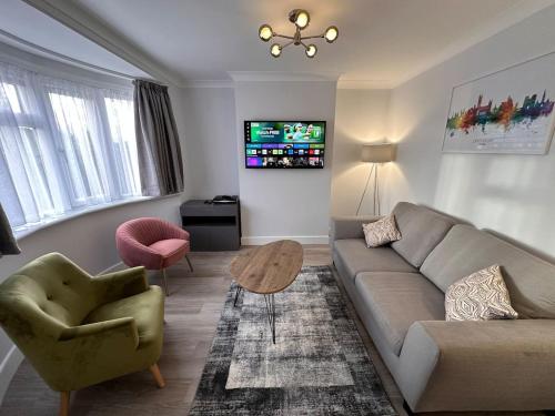 ein Wohnzimmer mit einem Sofa, einem Stuhl und einem TV in der Unterkunft City centre home in Canterbury with free parking in Canterbury