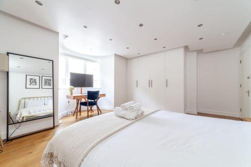 a white bedroom with a large bed and a desk at Stylish 3-bed near Camden Town & King's Cross in London