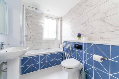 baño azul y blanco con aseo y lavamanos en Stylish 3-bed near Camden Town & King's Cross en Londres