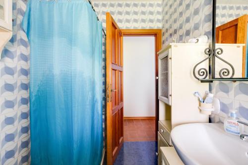 baño con cortina de ducha azul y lavamanos en Villa due Archi, en S'Archittu