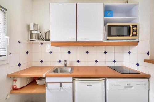 une petite cuisine avec un évier et un micro-ondes dans l'établissement Les maisons de Port Guillaume - maeva Home - Maison 3 pièces 6 personnes - Confort MAE-3464, à Dives-sur-Mer