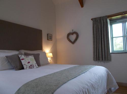 a bedroom with a bed with a heart sign on the wall at The Barn At Collacott in North Petherwin