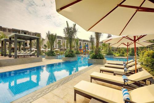 una piscina con sillas y sombrillas en un hotel en Kim's Villa - 5 phòng ngủ siêu rộng - 100m đến Bãi Tắm, en Ha Long