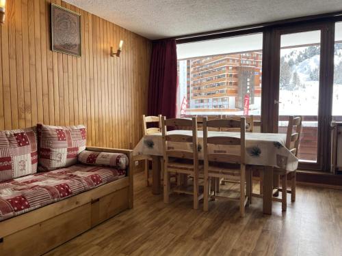 a dining room with a table and chairs and a window at Résidence Vercors - 3 Pièces pour 7 Personnes 474 in La Plagne Tarentaise