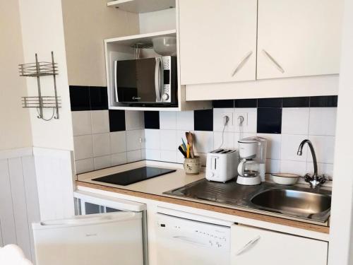 une cuisine avec un évier et un micro-ondes dans l'établissement Résidence Le Boucanier - 2 Pièces pour 4 Personnes 014, à Vieux-Boucau-les-Bains