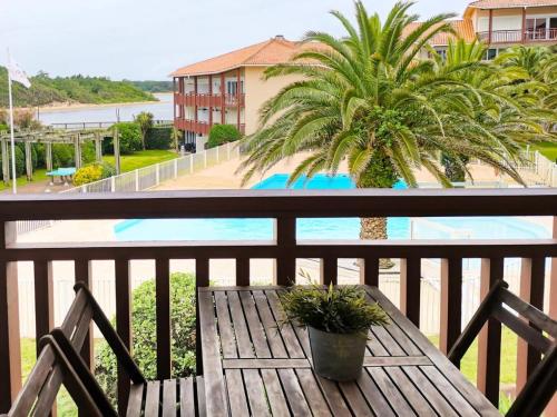 - une table en bois sur un balcon avec un palmier dans l'établissement Résidence Le Boucanier - 2 Pièces pour 4 Personnes 014, à Vieux-Boucau-les-Bains