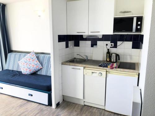 une petite cuisine avec des armoires blanches et un banc bleu dans l'établissement Résidence Le Boucanier - 2 Pièces pour 4 Personnes 084, à Vieux-Boucau-les-Bains