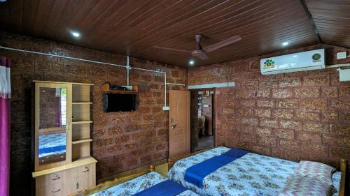 a bedroom with a bed in a room with brick walls at Tiny Waves in Udupi