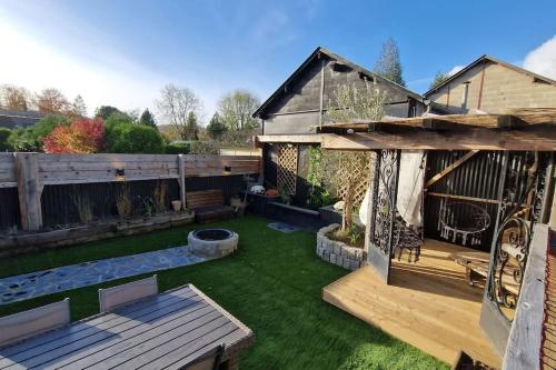 un jardin avec une pergola en bois et de la pelouse verte dans l'établissement Le Pont Joly, à Saint-Philbert-sur-Risle