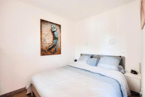 - une chambre dotée d'un lit blanc avec une photo sur le mur dans l'établissement Village Pont Royal en Provence - maeva Home - Appartement 3 pièces 6 personnes - Prestige MAE-4874, à Mallemort