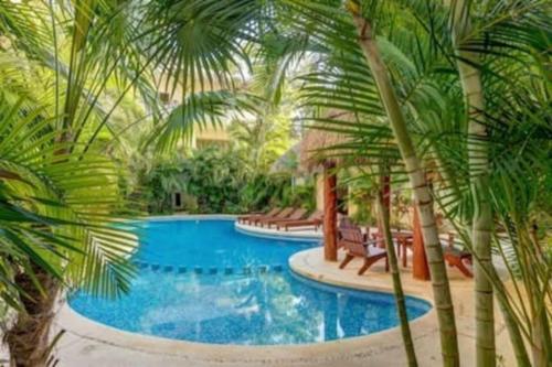 una piscina rodeada de palmeras en Condo Complex with an Alluring Pool & Tropical Vibes by Stella Rentals, en Tulum