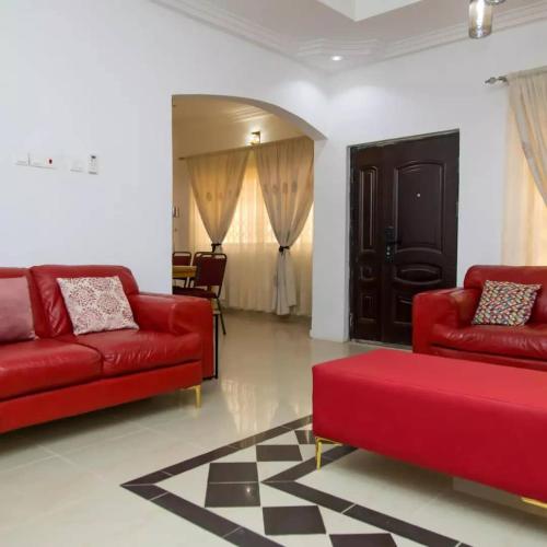 a living room with two red couches and a table at EdenRose home in Kwabenya