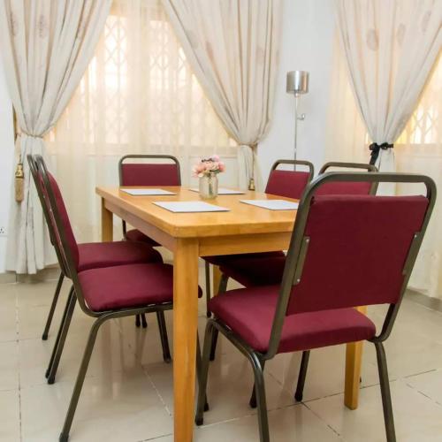 einen Holztisch mit roten Stühlen in einem Zimmer in der Unterkunft EdenRose home in Kwabenyan