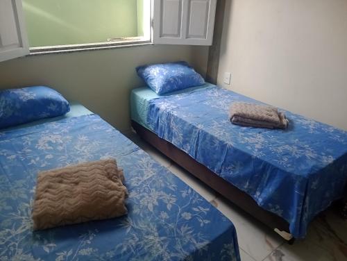 2 camas en una habitación con sábanas azules en Chalé Orange en Santa Cruz Cabrália