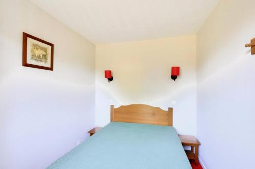 - une chambre avec un lit bleu et deux lumières sur le mur dans l'établissement La résidence du Lac - maeva Home - Appartement 2 pièces 5 personnes - Confort MAE-7384, à Monflanquin