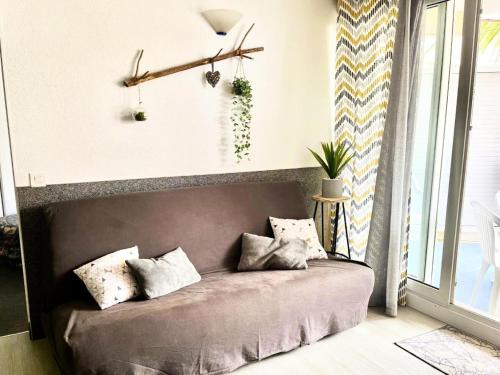 - un canapé avec des oreillers dans une chambre avec une fenêtre dans l'établissement Résidence Le Boucanier - 2 Pièces pour 6 Personnes 694, à Vieux-Boucau-les-Bains