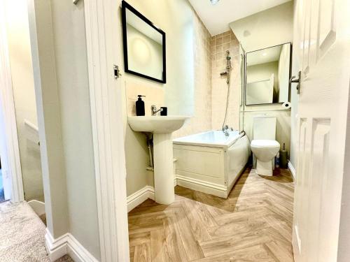 Baño blanco con lavabo y aseo en Stone Villas By Alternative Stays en Hednesford