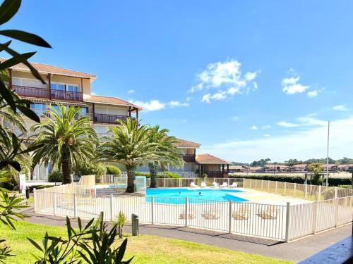 une villa avec piscine et palmiers dans l'établissement Résidence Le Boucanier - 2 Pièces pour 6 Personnes 694, à Vieux-Boucau-les-Bains