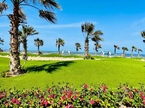 einen Park mit Palmen und Blumen und dem Meer in der Unterkunft غرفه وصاله علوى بورتو سعيد Porto Said Tourist resort in `Ezbet Shalabi el-Rûdi
