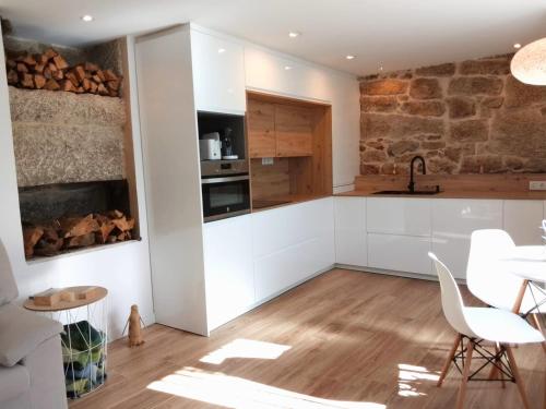 uma cozinha com armários brancos e uma parede de tijolos em Galician Holiday Home em Villariño