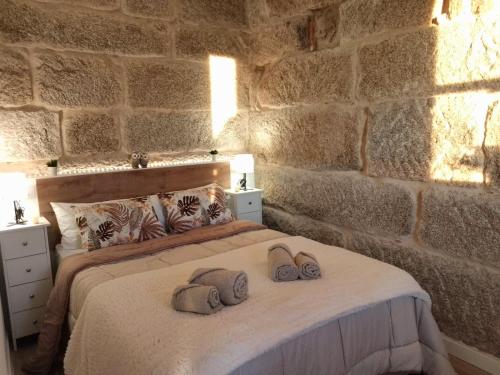 a stone walled bedroom with a bed with two pillows at Galician Holiday Home in Villariño