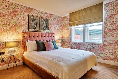 a bedroom with a large bed with floral wallpaper at Nest Serviced Apartments in Bedford