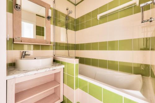 - une salle de bains verte et blanche avec lavabo et baignoire dans l'établissement Le Domaine du Bois de la Grée - maeva Home - Maison 3 pièces 6 personnes - Sélection MAE-7904, à Pornichet