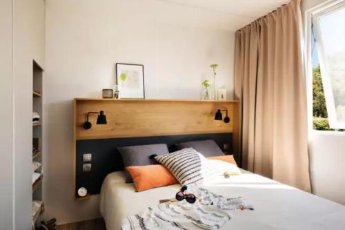 a bedroom with a bed with orange and white pillows at Mobilhome 4 étoiles - Piscine - eec0ib in Névez