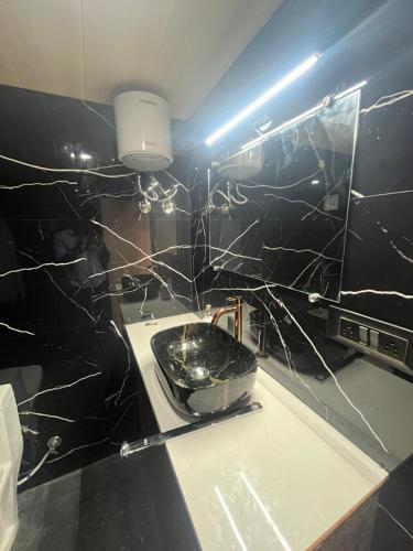 a bathroom with a black tiled wall with a toilet at AF Farm in Nagpur
