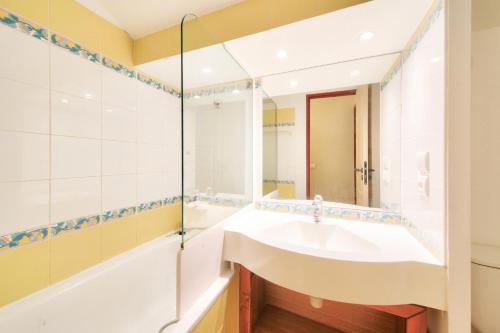 une salle de bain avec un lavabo, une baignoire et un miroir dans l'établissement Résidence La Marelle et Le Rami - maeva Home - Appartement 3 pièces 7 personnes - Sélection MAE-8764, à La Plagne Tarentaise