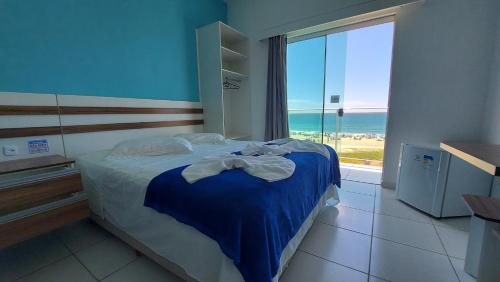 Hotel Pousada Agua Marinha في غواراتوبا: غرفة نوم مع سرير وإطلالة على المحيط