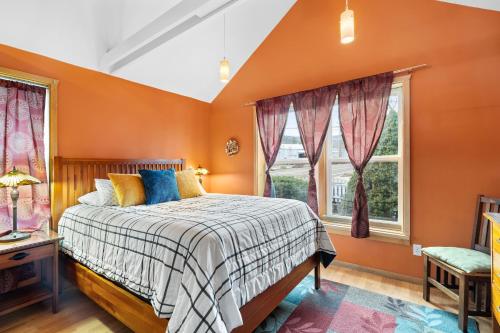 um quarto com paredes cor de laranja, uma cama e janelas em Bluemoon Vacation Rentals - Bluemoon Cottage em Ashland