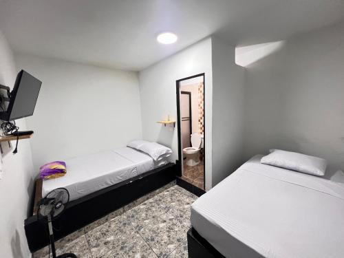 ein kleines Zimmer mit 2 Betten und einem Spiegel in der Unterkunft Nativos Hospedaje in Medellín