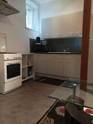 a kitchen with white appliances and a glass table at Appartement au calme. in Thaon-les-Vosges