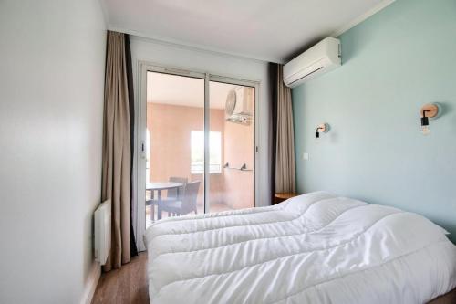 een wit bed in een kamer met een raam bij Village Pont Royal en Provence - maeva Home - Appartement 2 pièces 4 person 154 in Mallemort